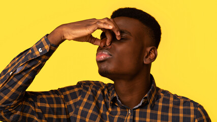 Bad Smell. Young african american guy closing his nose with fingers, irritated black millennial man...
