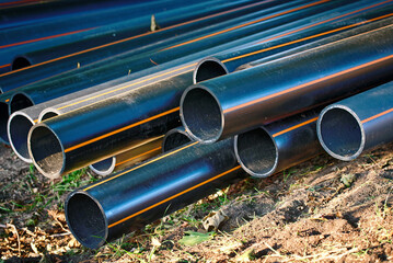 Multiple black hdpe pipes arranged at a construction site in the park for conduit network infrastructure related to underground electrical power distribution