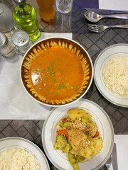 Paraguayan cuisine served in hotel. Local food of sopa de verduras (vegetable soup), panache de verduras (mixed vegetable dish), and rice on dining table, flat lay top angle vertical shot.