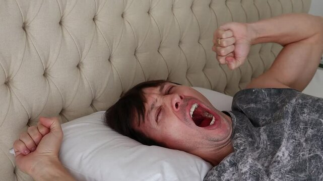homem acordando bocejando na cama 