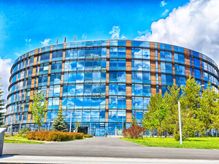 A contemporary office building showcases a striking glass facade that beautifully reflects the...