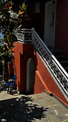 Red-tiled entrance with iron gate and stairs leading up to a traditional home in Thassos, Greece.