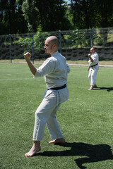 Man practicing karate in traditional uniform outdoors.