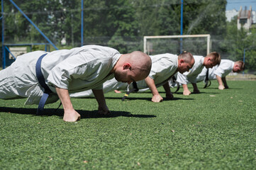 Obraz premium Karate students doing knuckle push-ups outdoors