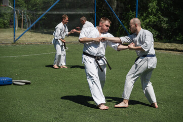 Obraz premium Karate students engaged in training sparring on outdoor field.