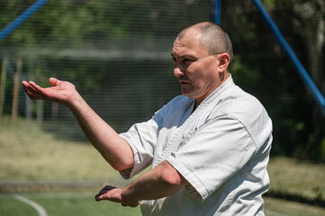 Man in white karate uniform practicing martial arts on a sports field.