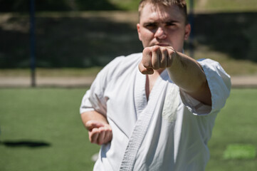 Man in white karate uniform practicing martial arts on a sports field.