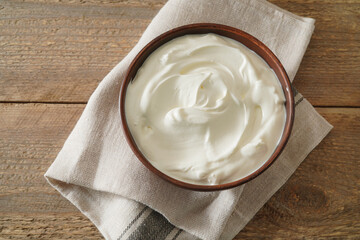 Sour cream in bowl on wooden table. Natural yogurt. Top view.