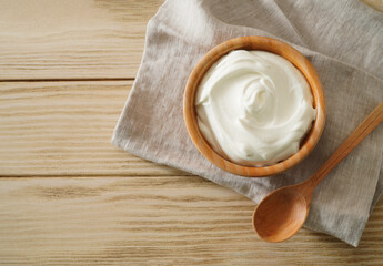 Sour cream in bowl on wooden table. Natural yogurt. Top view.