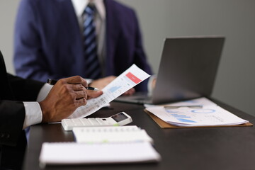 Businessman is calculating profit and analyzing financial data on report in office. Advisor is...