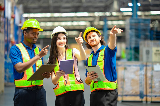 Three industrial workers planning logistics operations, wearing safety gear and using tablets. Modern warehouse teamwork, supply chain management, and organization. - Powered by Adobe