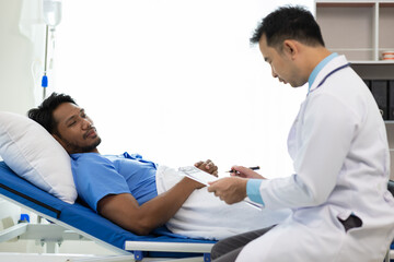 Obraz premium Doctor taking notes while patient explaining symptoms in hospital room. Doctor listens to a patient's symptoms in a hospital room, taking notes on a clipboard.