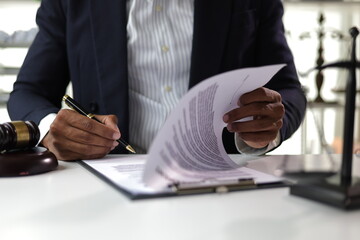 Lawyer reading legal documents and preparing to sign a contract. Lawyer is carefully reviewing...