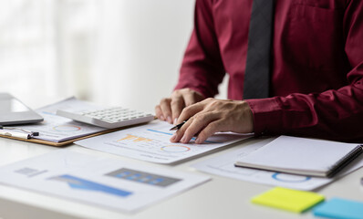 Businessman using calculator analyzing financial business charts.