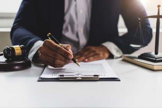 Lawyer reading legal documents and preparing to sign a contract. Lawyer is carefully reviewing legal documents at his desk.