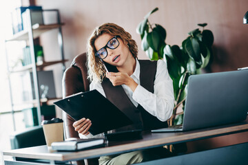 Confident businesswoman multitasking in a professional office environment with modern workspace and...