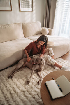 A woman is enjoying some time relaxing with her pet dog in a cozy living room setting