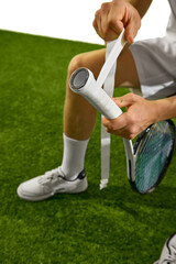 A tennis player adjusts their racket grip on a grass court, focusing on the hands and equipment....