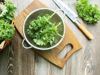 Fresh green curly kale leaves on a wooden table.
