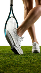 A tennis player's legs and racket are seen resting on a grassy court, with athletic shoes against a...