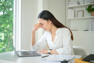 Obraz premium Businesswoman feeling anxious and fatigued while working ar her desk