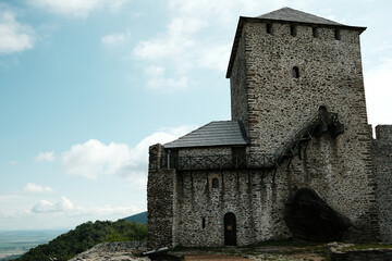 Fototapeta premium Full view of the Vrsac Fortress with stone wall and tower, standing tall on a grassy hill. Travel in Serbia country concept. A popular tourist destination