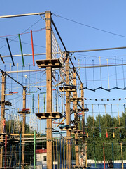Adult man climbing and balancing on high ropes obstacle course in adventure park. Outdoor summer activity, sports entertainment, zipline and rope bridges. Active recreation and extreme training.