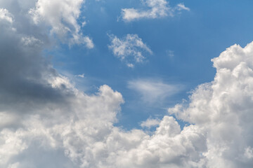 Multilevel white clouds at the edges of the frame converge toward the center in a blue sky close-up, view among the clouds high in the sky, close-up clouds, airy white clouds, and the sky.