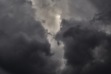 A layer of gray clouds interspersed with sun rays, creating a contrast of light and shadow. A...