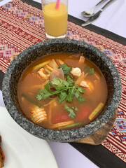 Traditional Thai Tom Yum soup with shrimp, lemongrass, chili, lime, and mushrooms served in a bowl. Spicy Asian cuisine close-up. Authentic exotic food with vibrant colors and aromatic herbs.