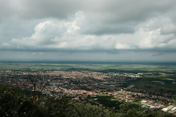 Wide panoramic view of Vrsac and surrounding Serbian countryside under a dramatic cloudy sky in...