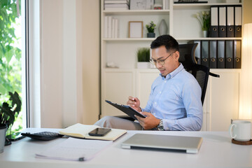 Focused businessman checking reports at his desk in a bright and modern office.