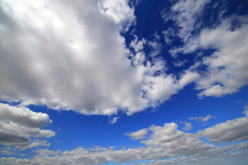 Scattered clouds stretch across a vivid blue sky in a calm and expansive daylight view