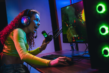 Crazy woman enjoying online gaming session with neon lights at home, highlighting technology and...