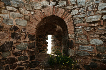 Obraz premium Archway passage in Ram Fortress with wildflowers and stone textures. A popular tourist destination in Serbia country
