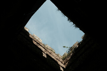 View from inside a medieval stone tower looking up at the blue sky, with plants growing on the upper edges of the walls. Ram Fortress, Serbia
