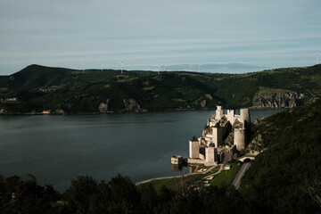 Elevated view of Golubac Fortress on the Danube, surrounded by lush green hills and blue sky. A popular tourist destination