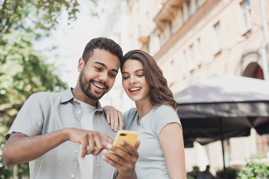 Beautiful happy young couple using smartphone outdoors, Joyful smiling woman and man looking at mobile phone in a city, Love, technology, communication, summer travel concept