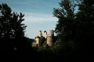 Golubac Fortress at sunset rising between dense trees, captured at sunset from a shaded forest path. A popular tourist destination in Serbia
