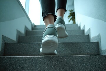 Modern casual footwear worn by person walking up gray staircase indoors with natural light and minimal decor in contemporary setting