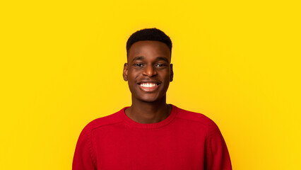 Portrait Of Cheerful Millennial Black Guy In Red Sweater Over Yellow Background, Positive Young African American Man Looking And Smiling At Camera While Posing In Studio, Closeup Shot, Copy Space