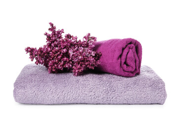 Soft towels and lilac flowers isolated on white