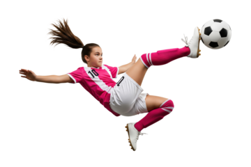 Focused girl soccer player kicking ball in midair wearing pink uniform