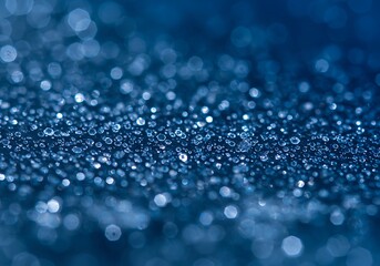 Water droplets sparkle on a blue surface in a macro close up