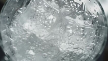 Pouring sparkling water over ice cubes in an elegant glass, close-up. - Powered by Adobe