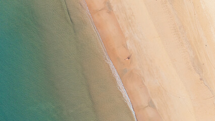 Bird's eye top aerial view of woman relaxing in sandy beach in the pristine turquoise shoreline and sweeping coastal landscape of Nacpan Beach in El Nido, Palawan, Philippines