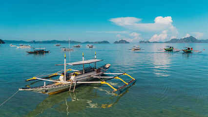 Bangka boats resting in Clear Skies and Peaceful Blue Horizon Over Coastal Paradise of El Nido’s Corong Corong Beach