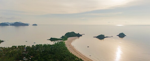 Stunning aerial view of Nacpan Beach’s winding shore, vibrant tropical greenery, and sparkling clear sea in El Nido, Palawan, Philippines