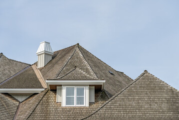Top of grey stucco luxury house with shingle roof, green trees and nice windows in Spring in Vancouver, Canada, North America. Day time on May 2025.
