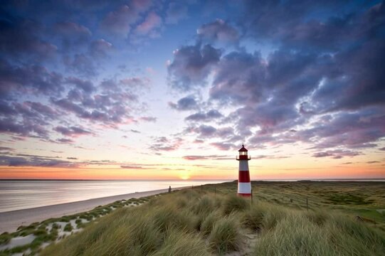 Breathtaking Sunrise on Sylt: A Majestic Lighthouse Surrounded by Dunes and Soaring Birds